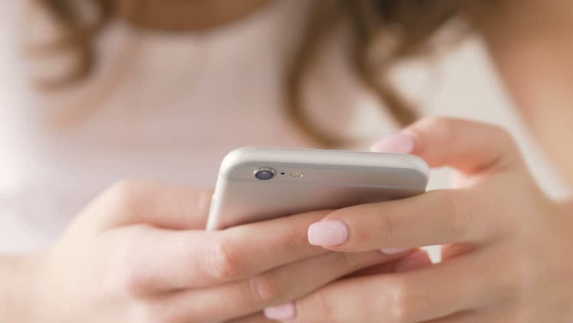 Chica con smartphone en la mano escribiendo